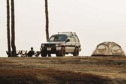 SUV og kuppeltelt på en åpen høyde med folk i campingstoler