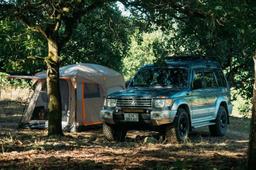 SUV parkert i skogen med et stort telt montert bak på bilen