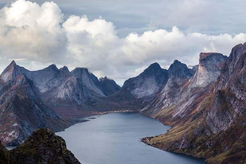 Dramatiske svarte fjelltopper ved en stille fjord